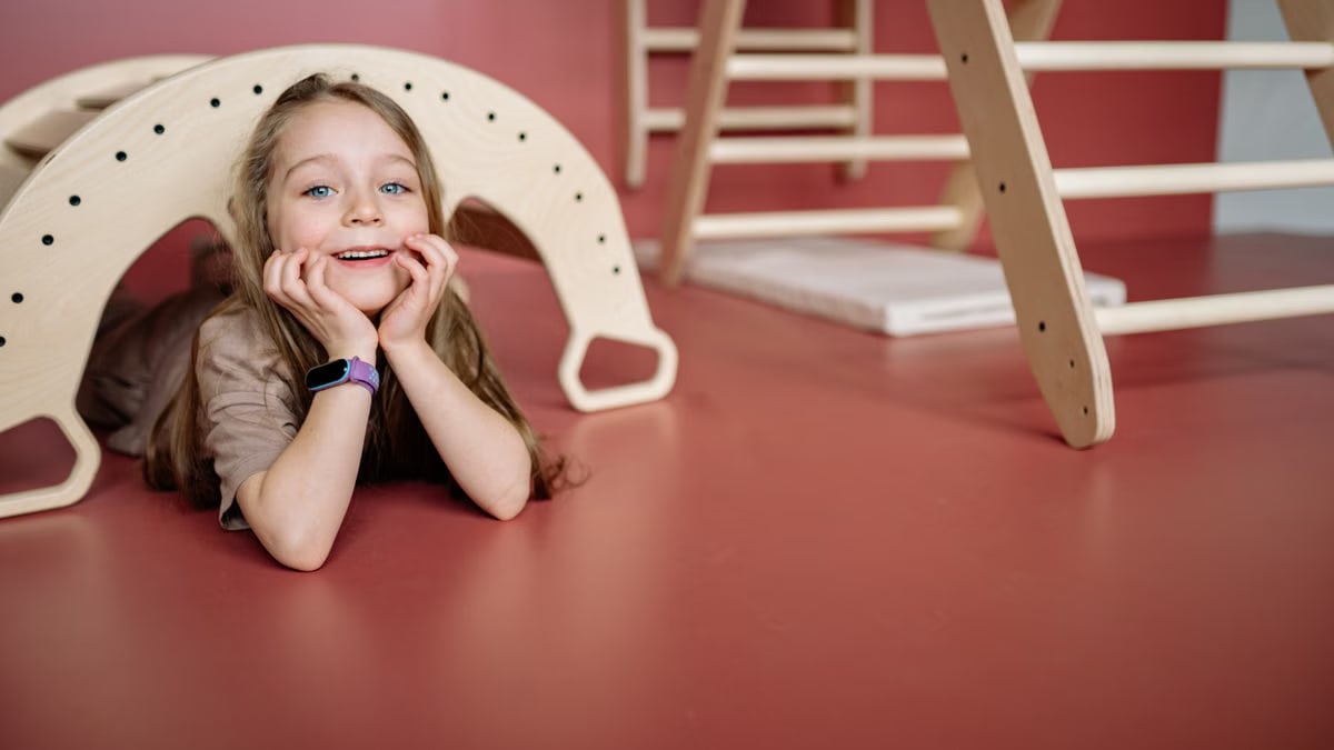 A joyful child playing with a wooden toy bridge indoors, smiling and having fun.